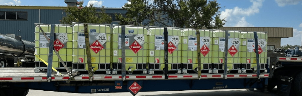 Flatbed truck loaded with flammable liquid containers for HAZMAT transport